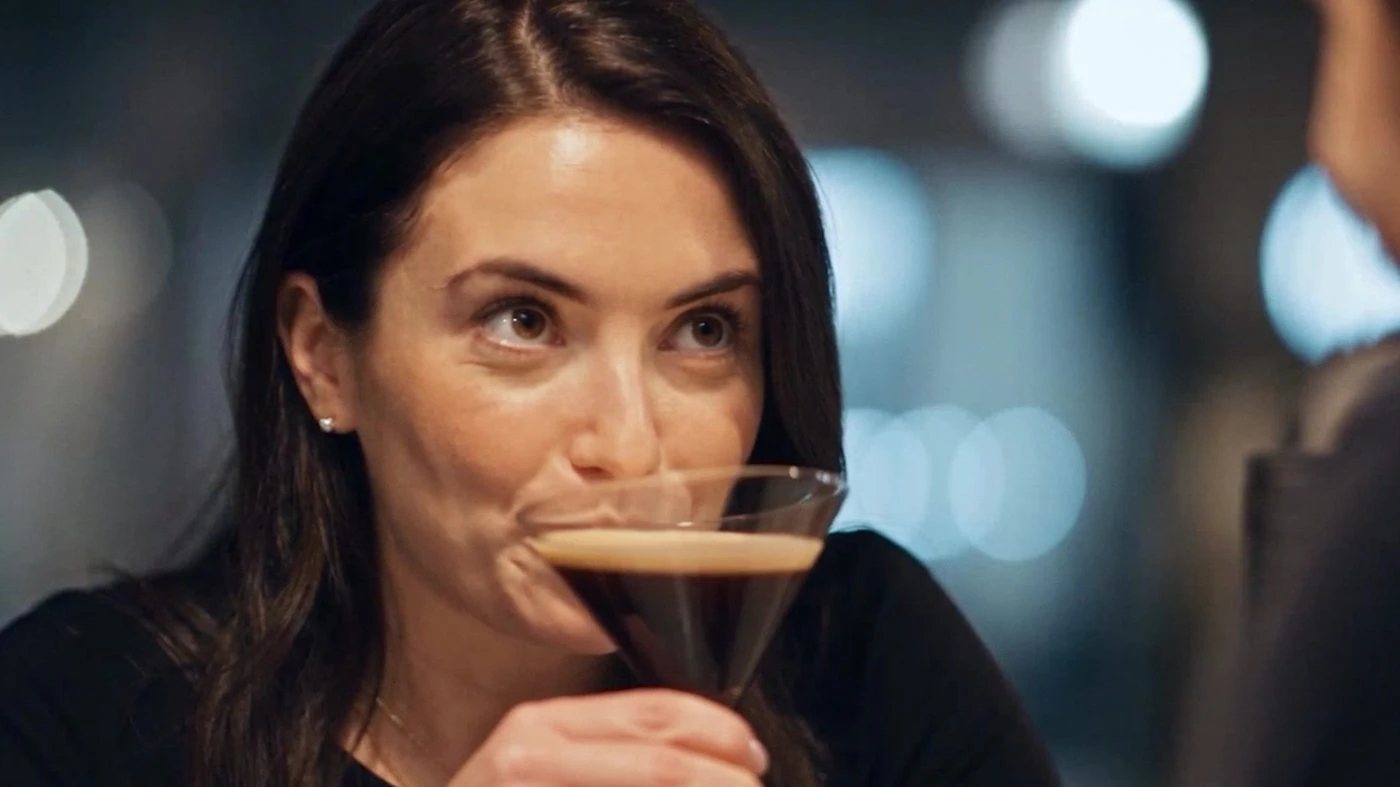 AI version: close-up of the woman holding her espresso martini during the closing exchange