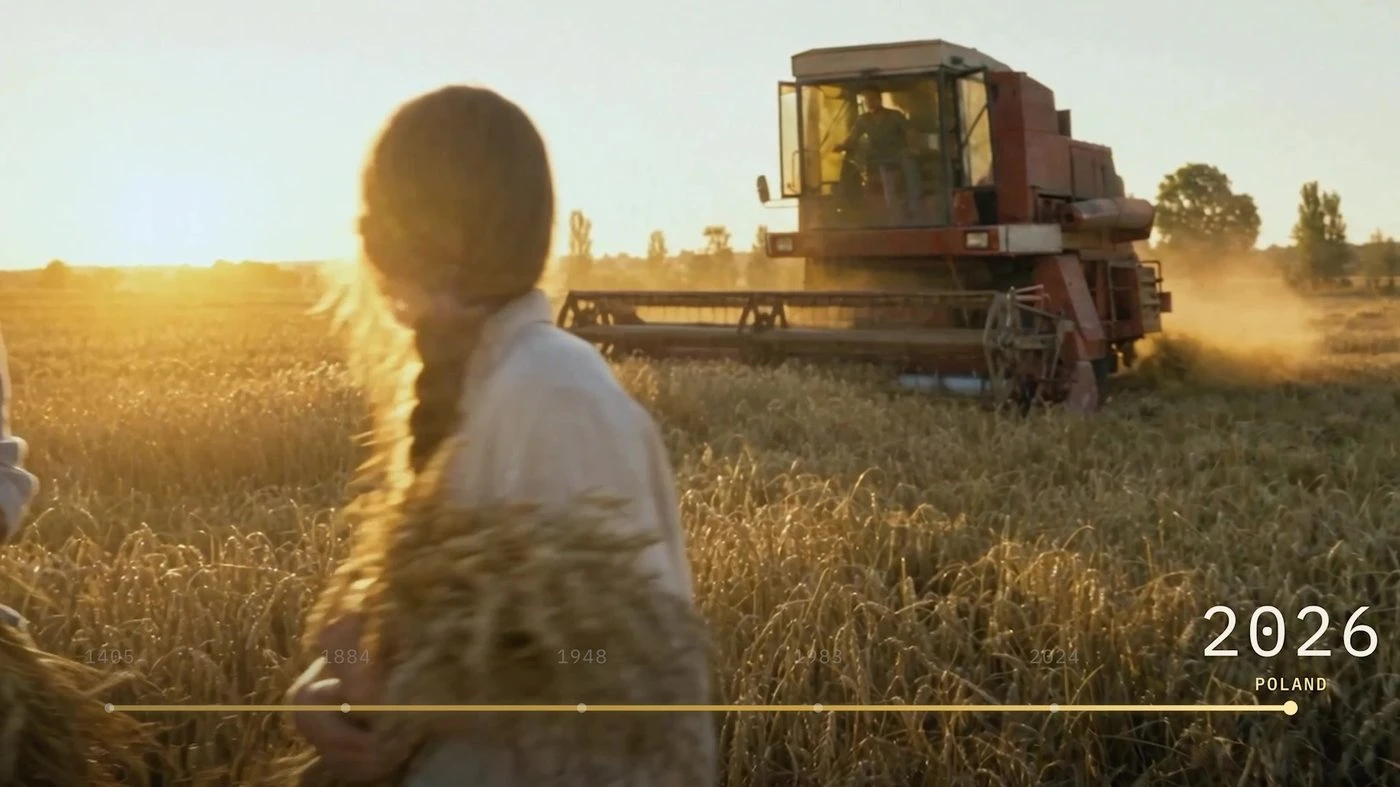 A woman in a Polish grain field with a combine harvester in the background
